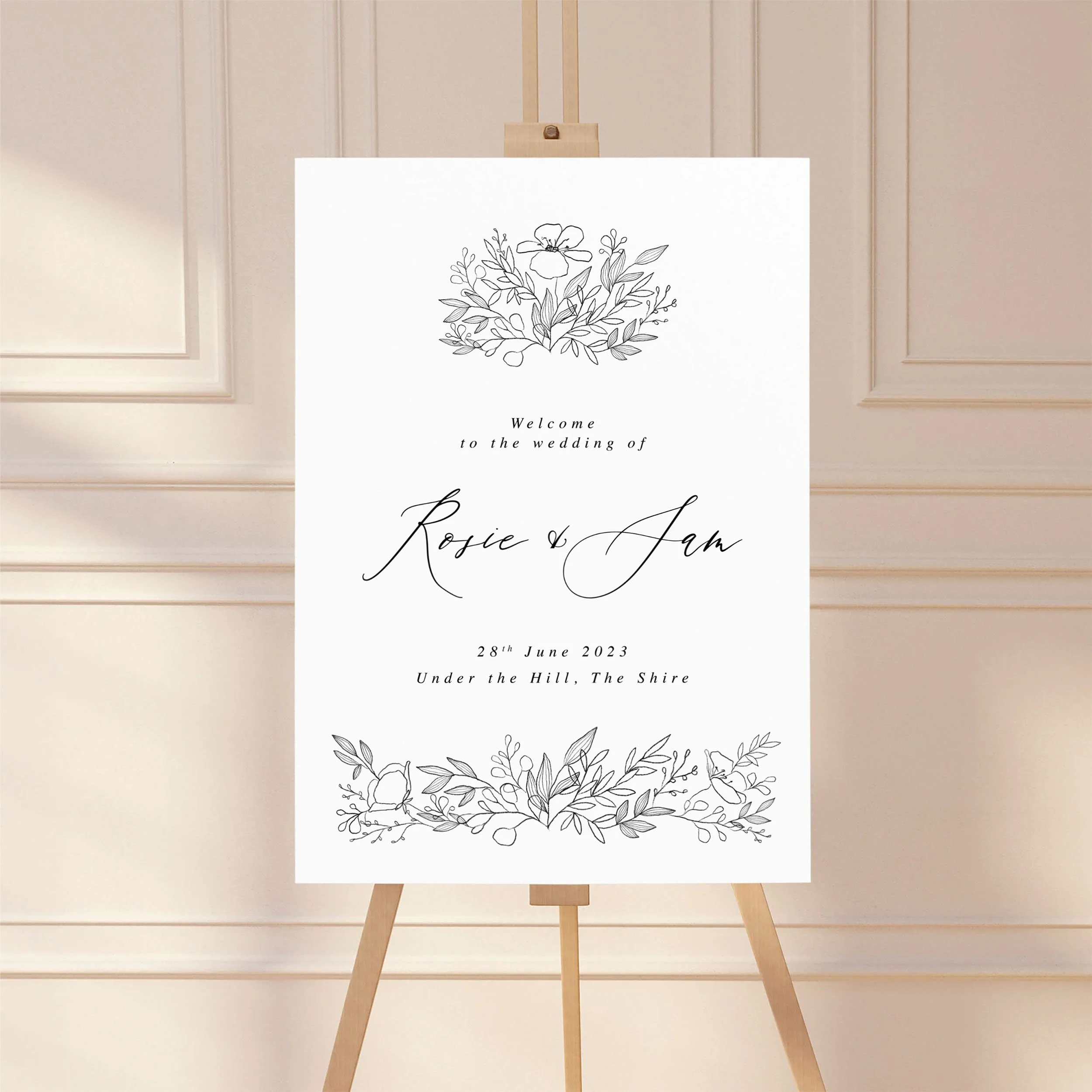 A large wedding welcome sign on an easel with a monochrome black floral sketch design.