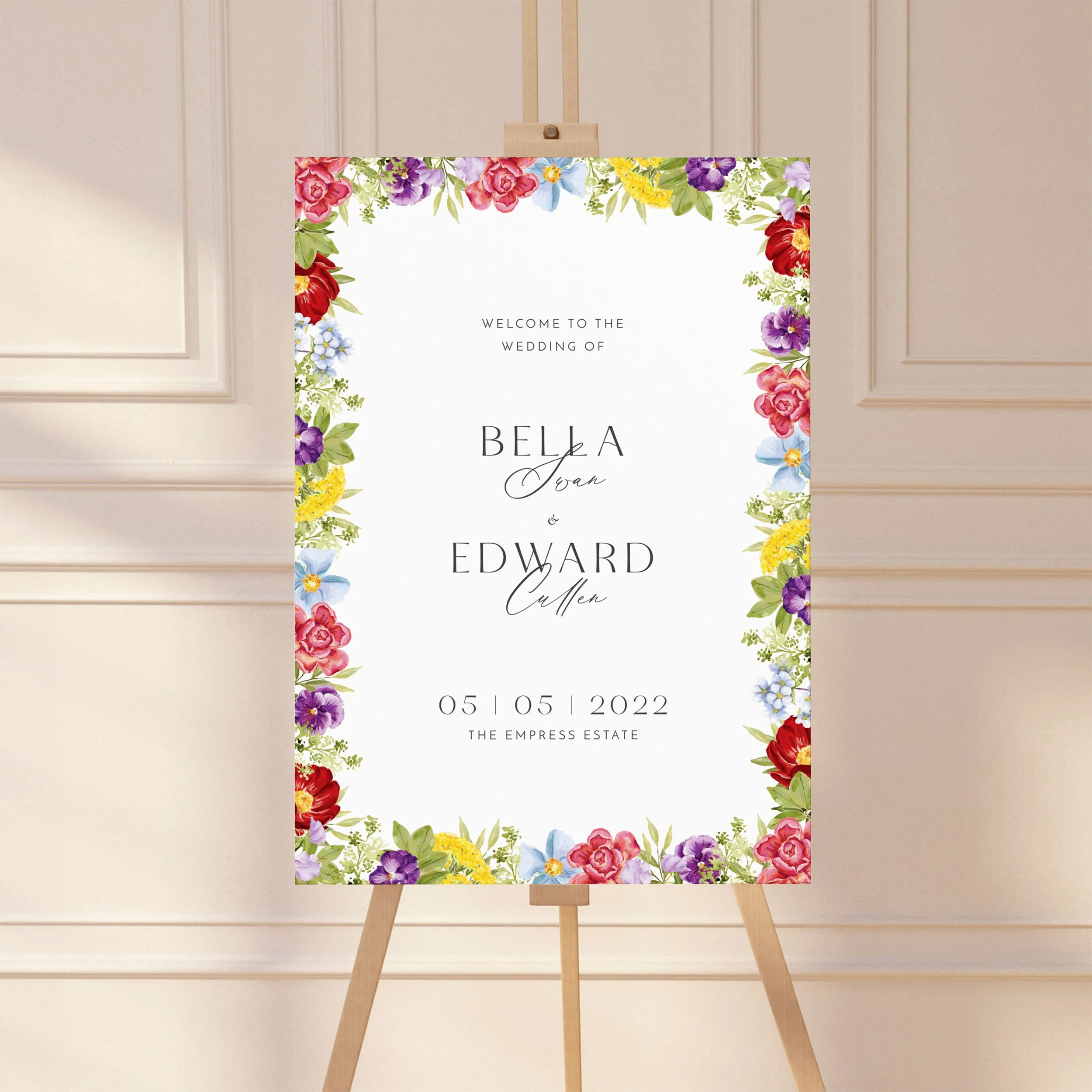 A large wedding welcome sign on an easel with a bold floral border design.