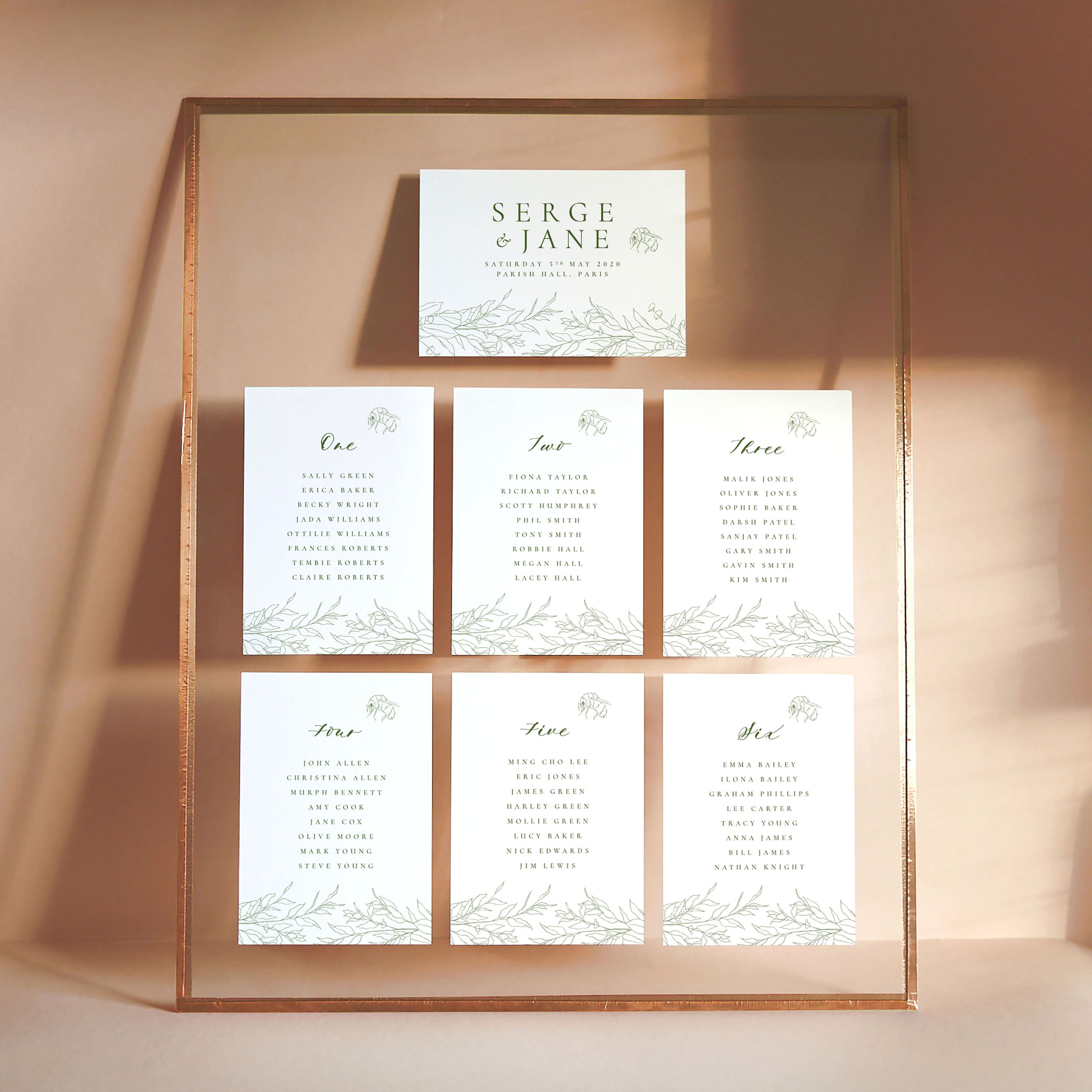 A set of small A6 printed table plan cards in a glass frame with copper edges. The design has hand drawn botanical elements framing the top and bottom and a cute bumblebee motif.