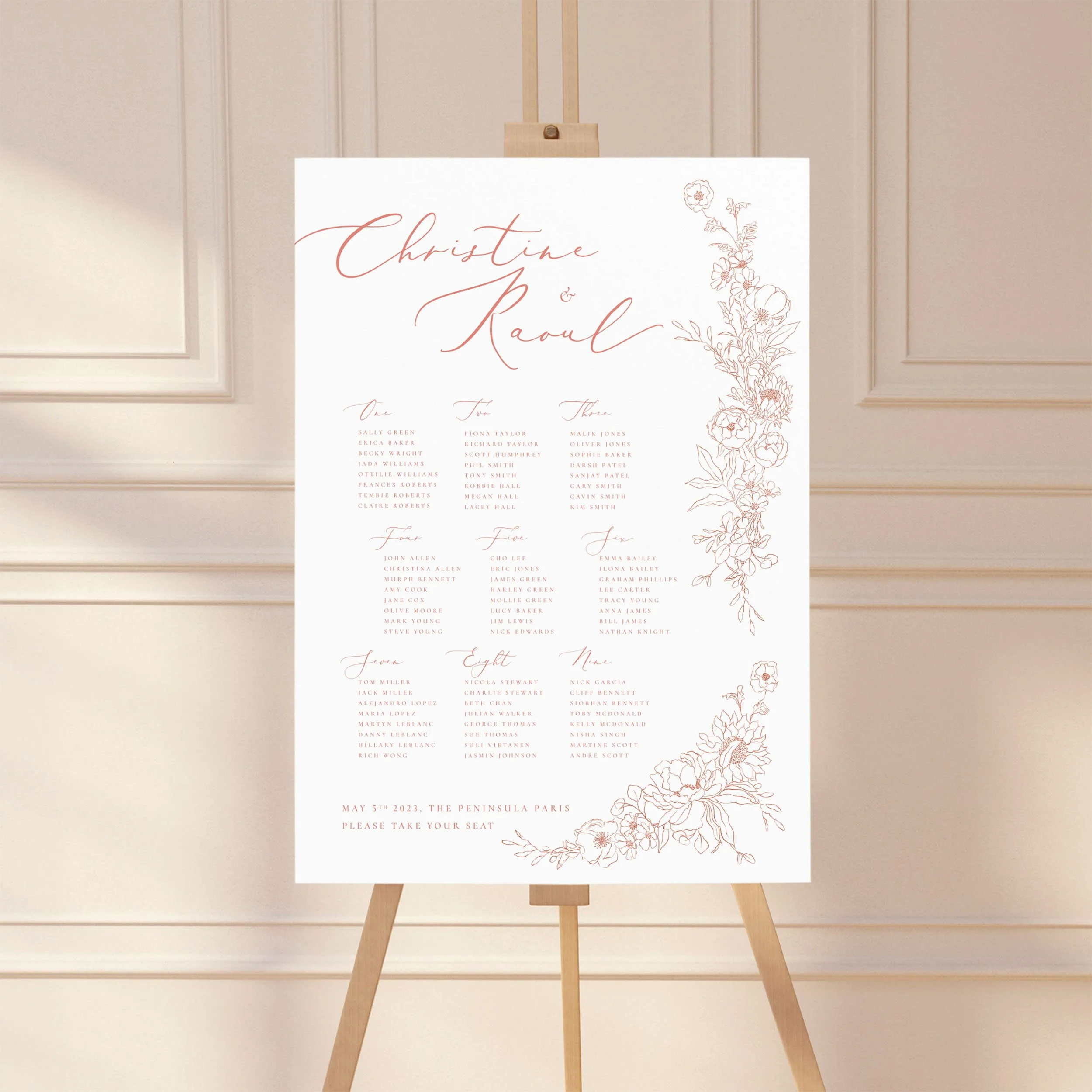 A wedding table plan sign printed on a large A1 board, standing on an easel. The design has illustrated flowers and leaves spilling down the right-hand side.