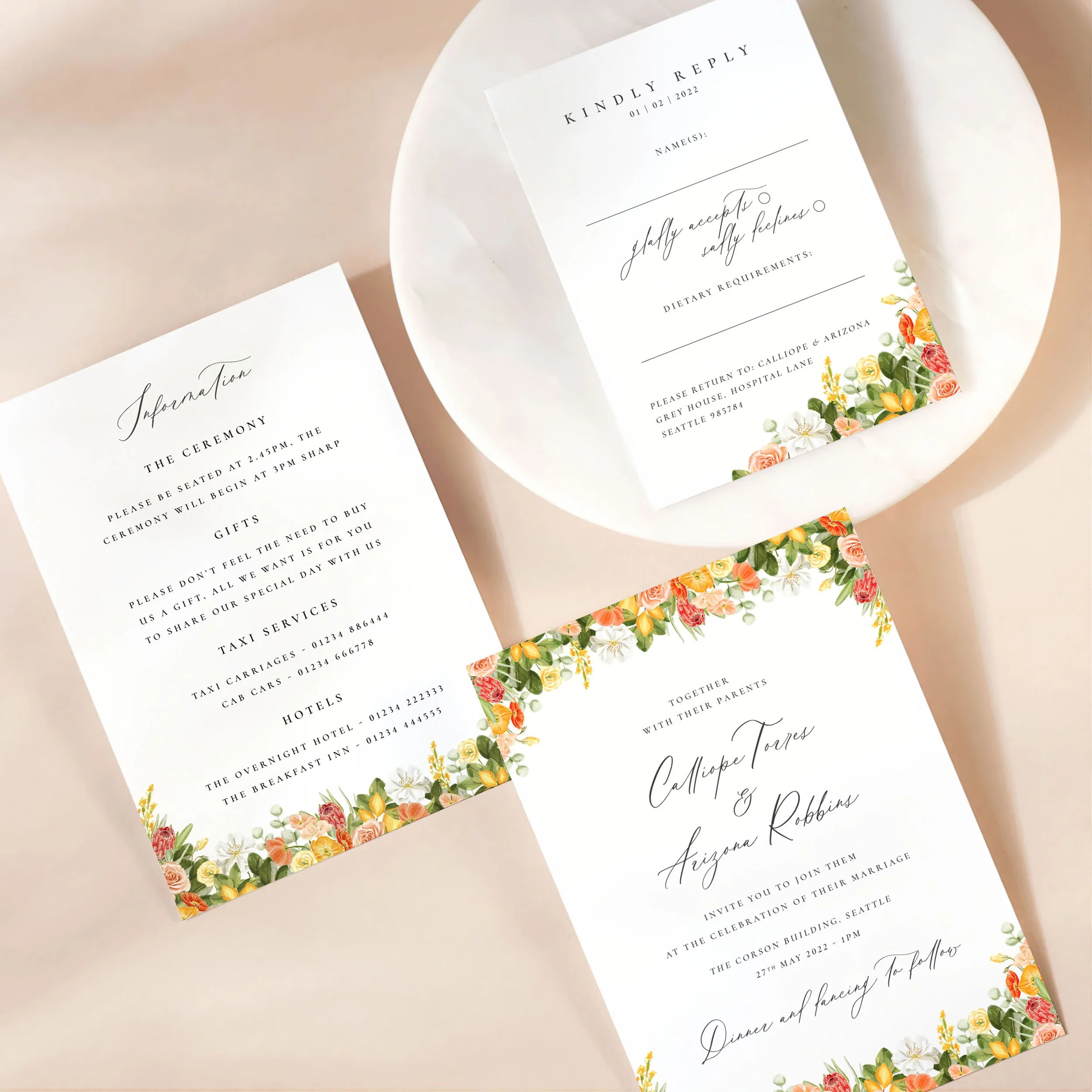 A wedding invitation card with details card and rsvp on a marble dish. There is a colourful hand-painted lemon and flower design on each card.