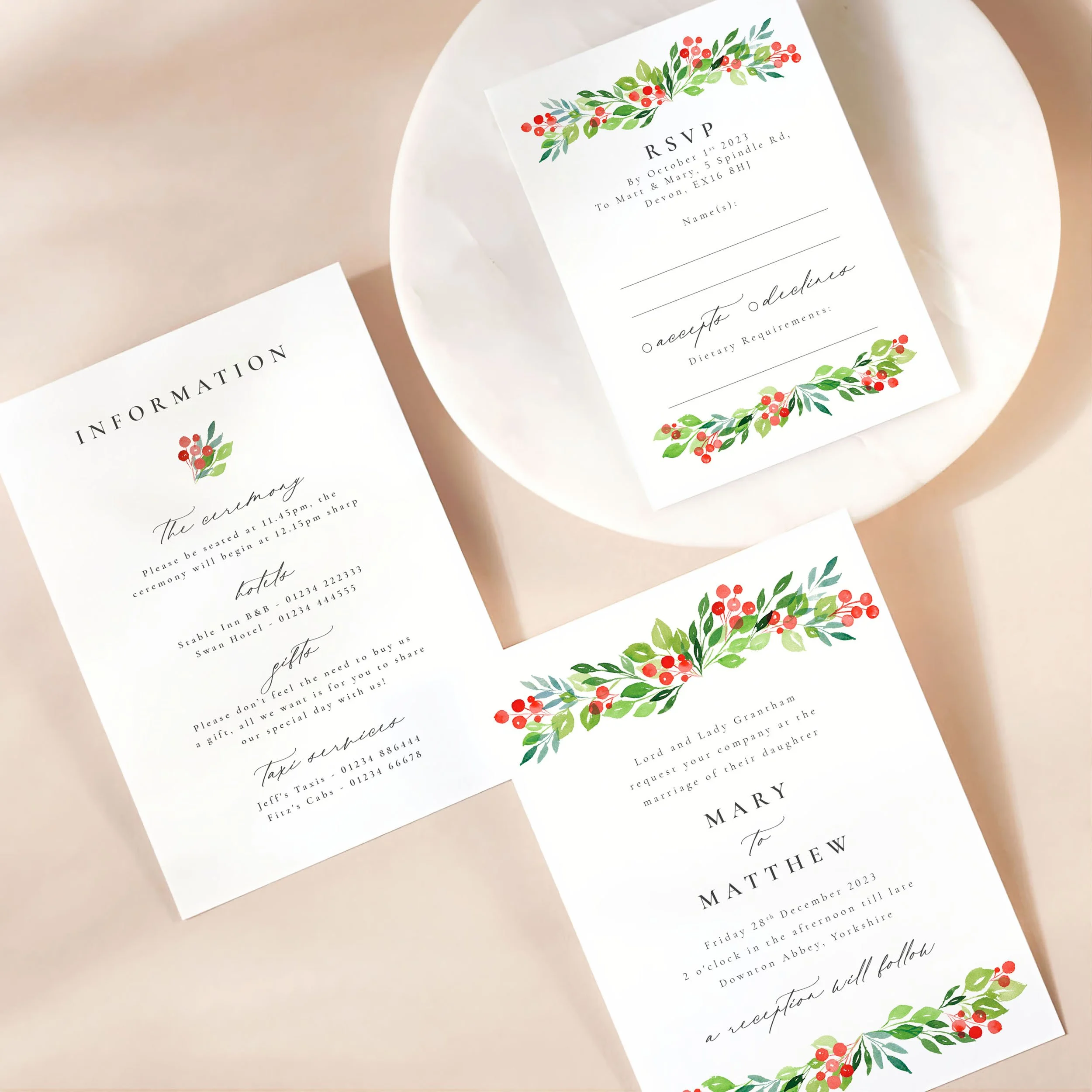 A wedding invitation card with details card and rsvp on a marble dish. There is a bright watercolour winter berries design on each card.