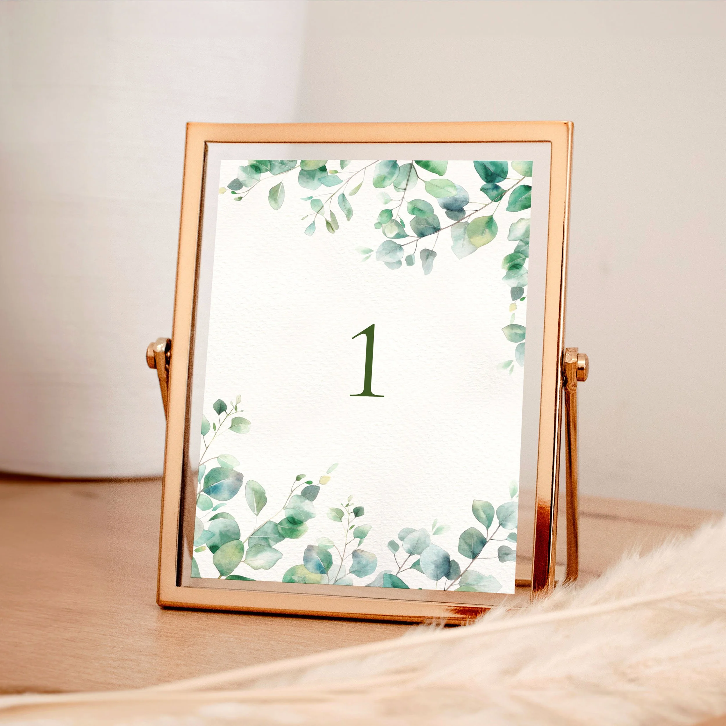 A table wedding number card in a rose gold frame with green watercolour eucalyptus leaves