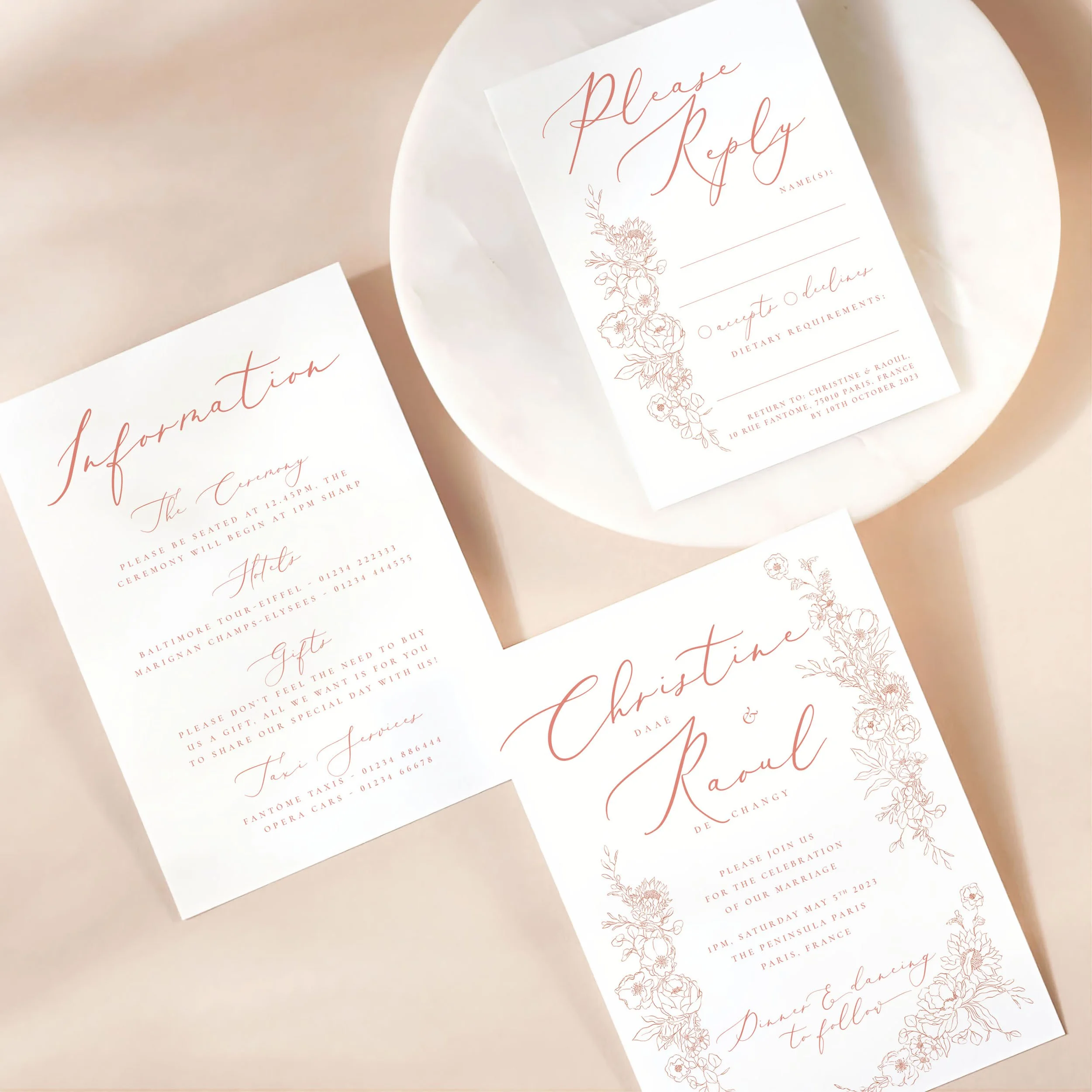 A wedding invitation card with details card and rsvp on a marble dish. There is a vintage-style flowery pink motif design on each card.