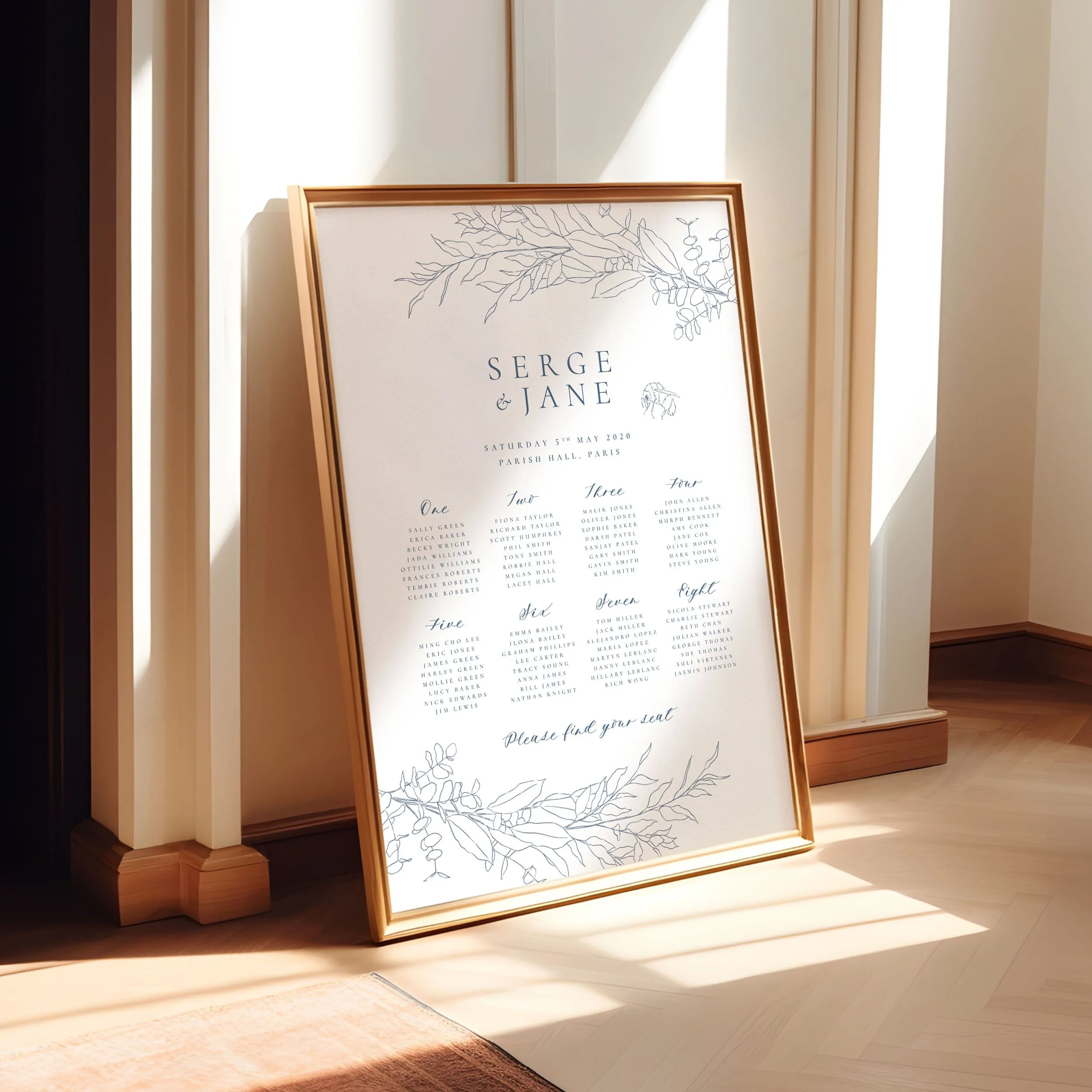 A framed A1 table plan sign leaning against a wall as the light spills across. The design has a delicate hand drawn bumble bee and leaves in dusty blue.