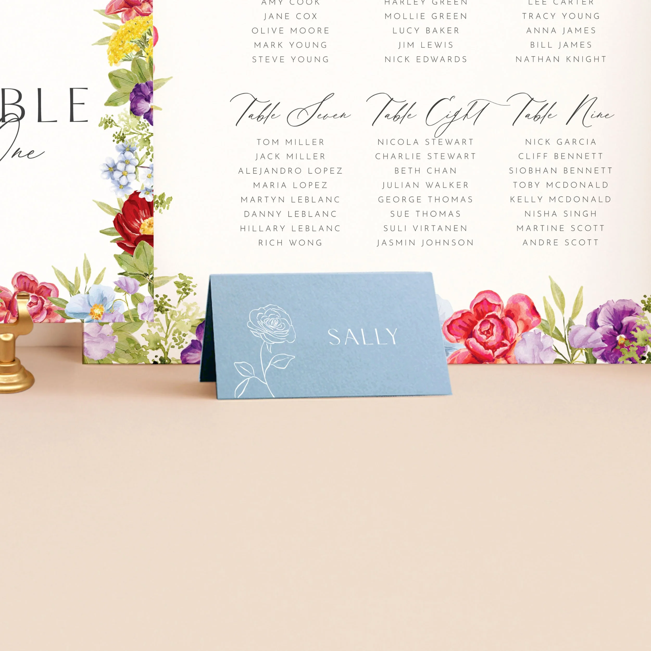 A light blue tent place card, printed in white ink with a guest name and a small rose illustration.