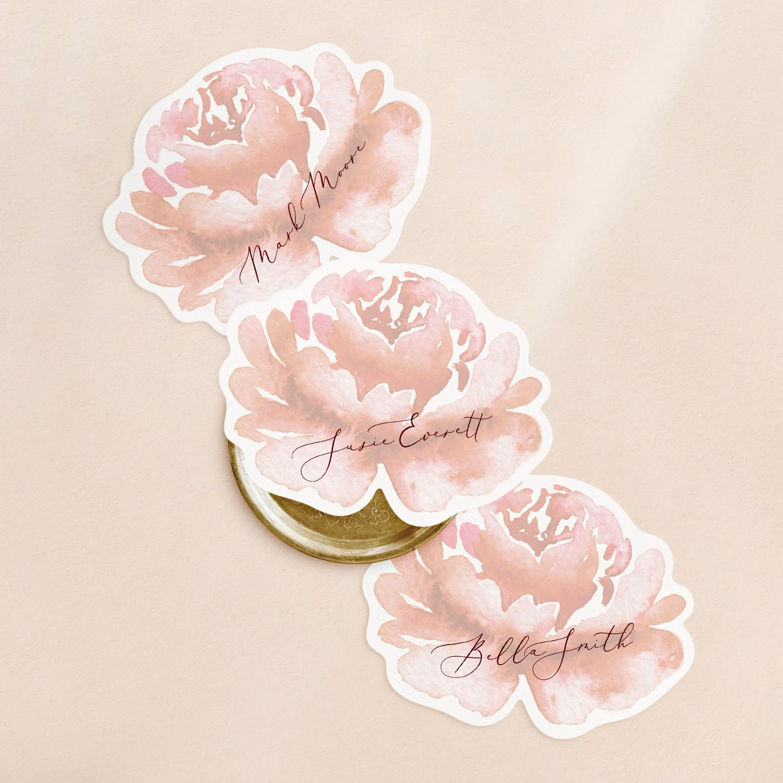 Three flower shaped wedding place cards with a faded red watercolour flower and guest name printed.