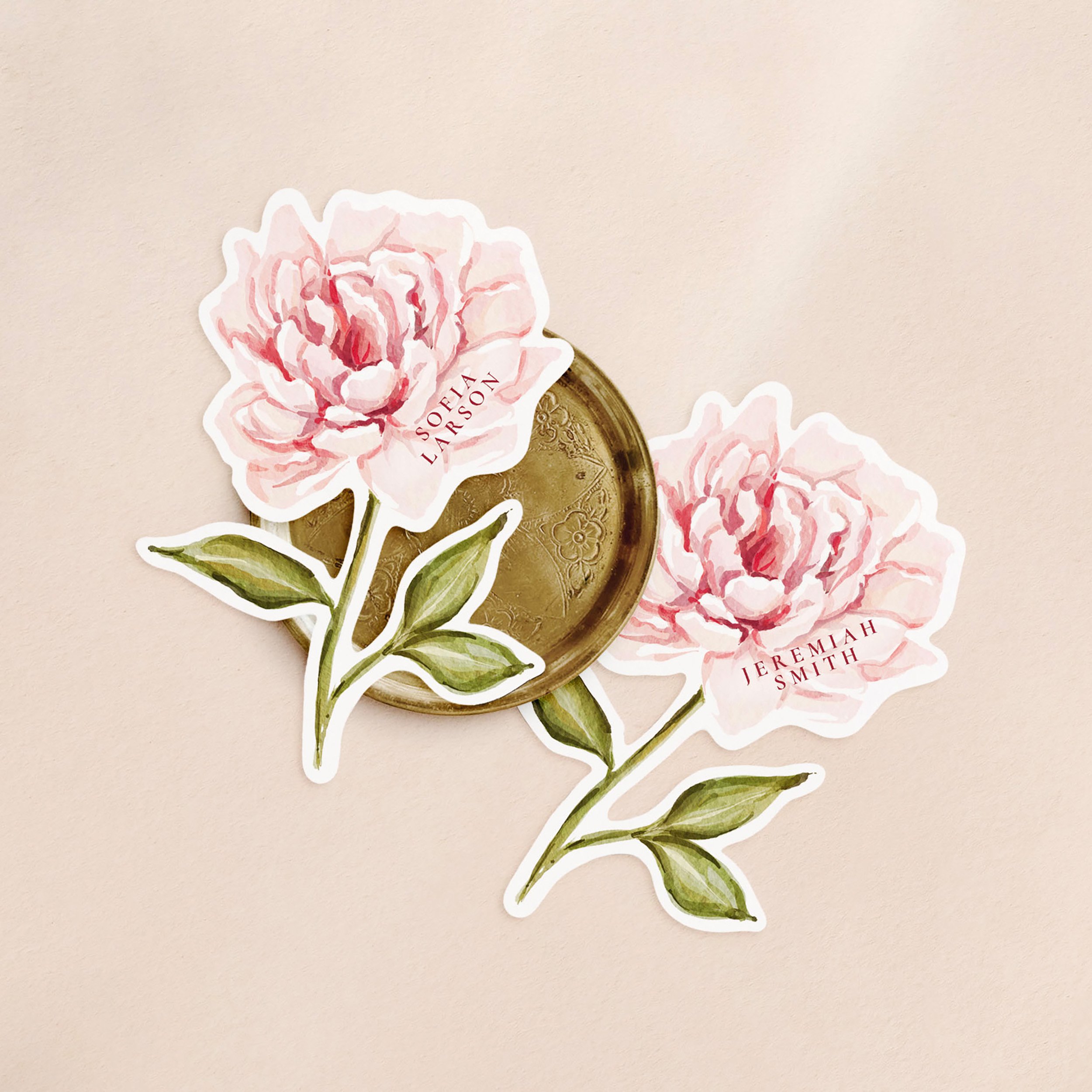 Two flower-shaped place cards with a faded hand-painted peony and a different guest name printed on each.