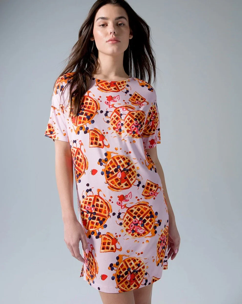 A woman wearing a pink dress with a repeated pattern of waffles, strawberries, and blueberries.