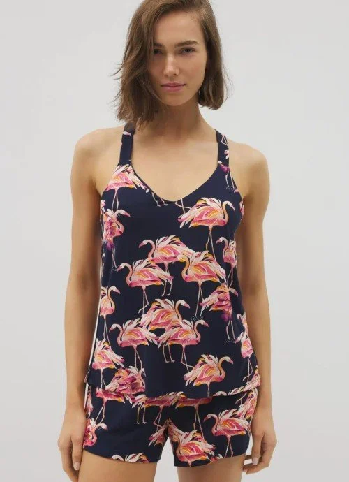 Young woman wearing a navy tank top and matching shorts with pink flamingo print, standing against a plain light gray background.