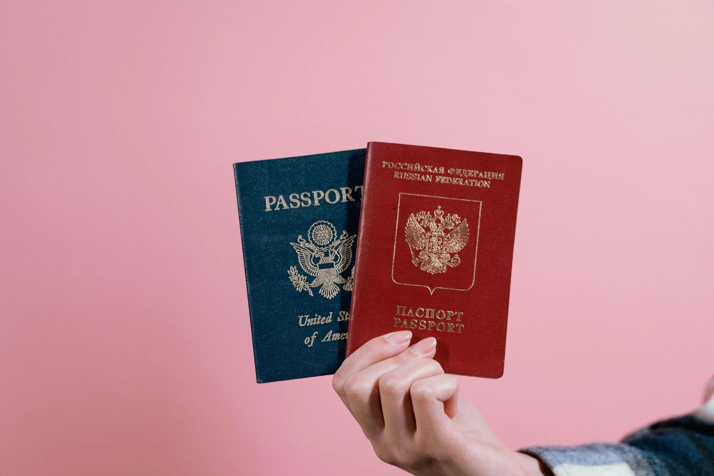 Person Holding Red and Blue Passports