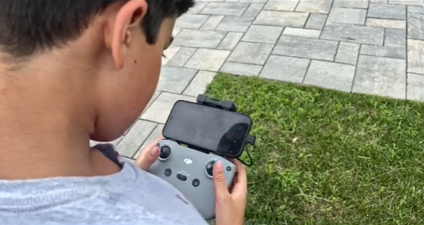 Speaking & Learning: Student operating a drone controller during a JKS filmmaking program.