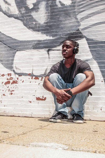 John Kind Sitting down listening to music with headphones.