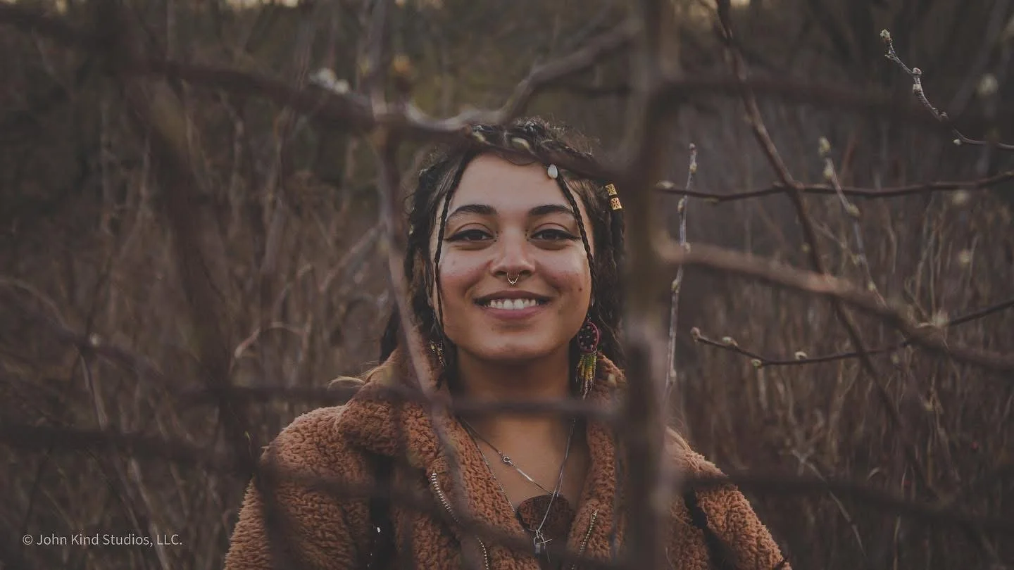 Artist Eva Davenport smiling during an outdoor portrait session photographed by John Kind Studios.