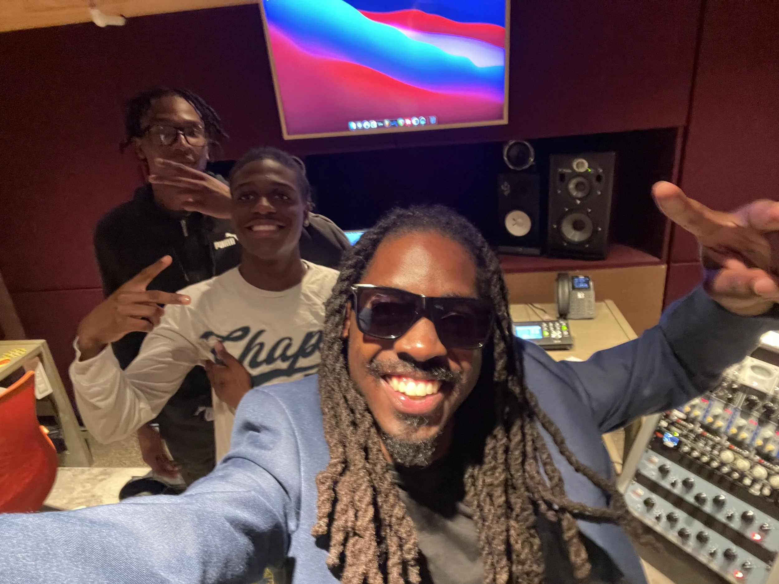 John Kind with two high school students during a hands-on audio production experience in a professional recording studio.