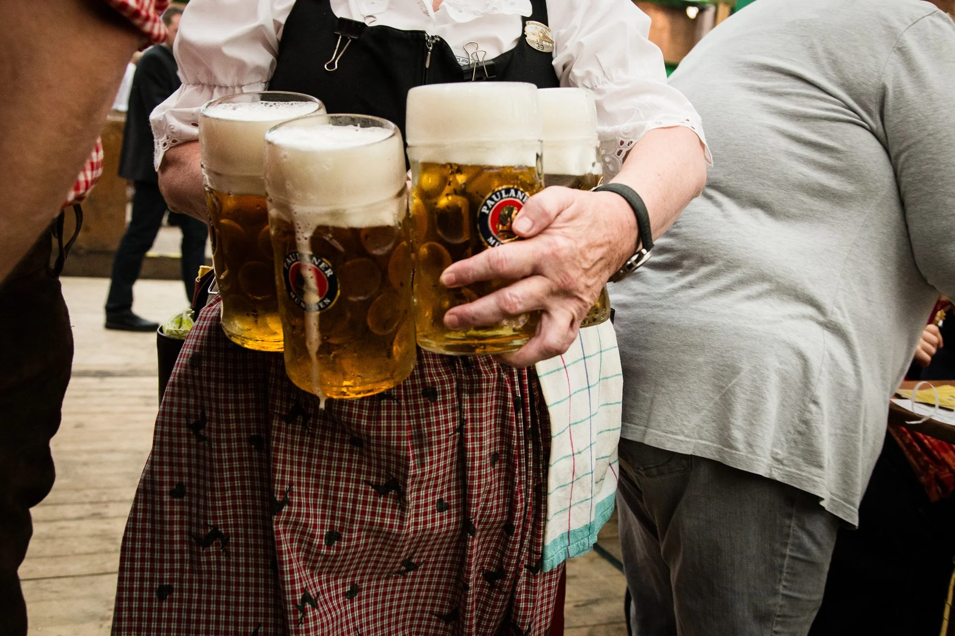 A waitress in a traditional Bavarian dirndl serves pitchers of beer.