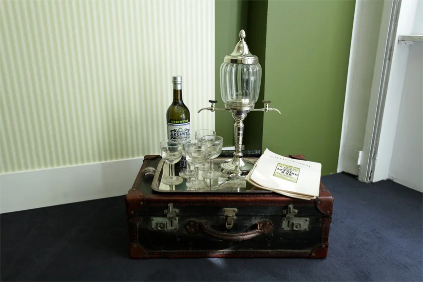 «Time Travel Box» (2012) Briefcase, absinthe fountain, bottle, glasses, sugar, magazines. 72 x 60 x 37 cm Ed: Unique - Installation view: Lars Morell «Hotel Paris» Galerie Nivet-Carzon, Paris. 16.09 - 20.10.2012.