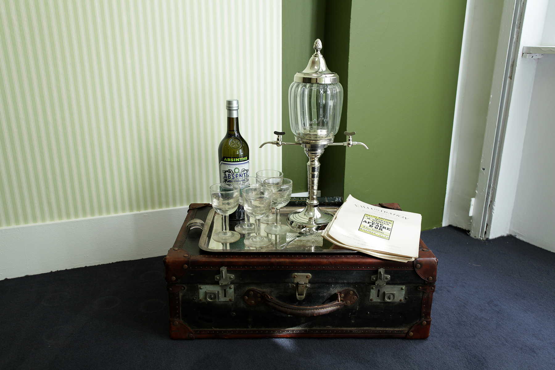 «Time Travel Box» (2012) Briefcase, absinthe fountain, bottle, glasses, sugar, magazines. 72 x 60 x 37 cm Ed: Unique - Installation view: Lars Morell «Hotel Paris» Galerie Nivet-Carzon, Paris. 16.09 - 20.10.2012.