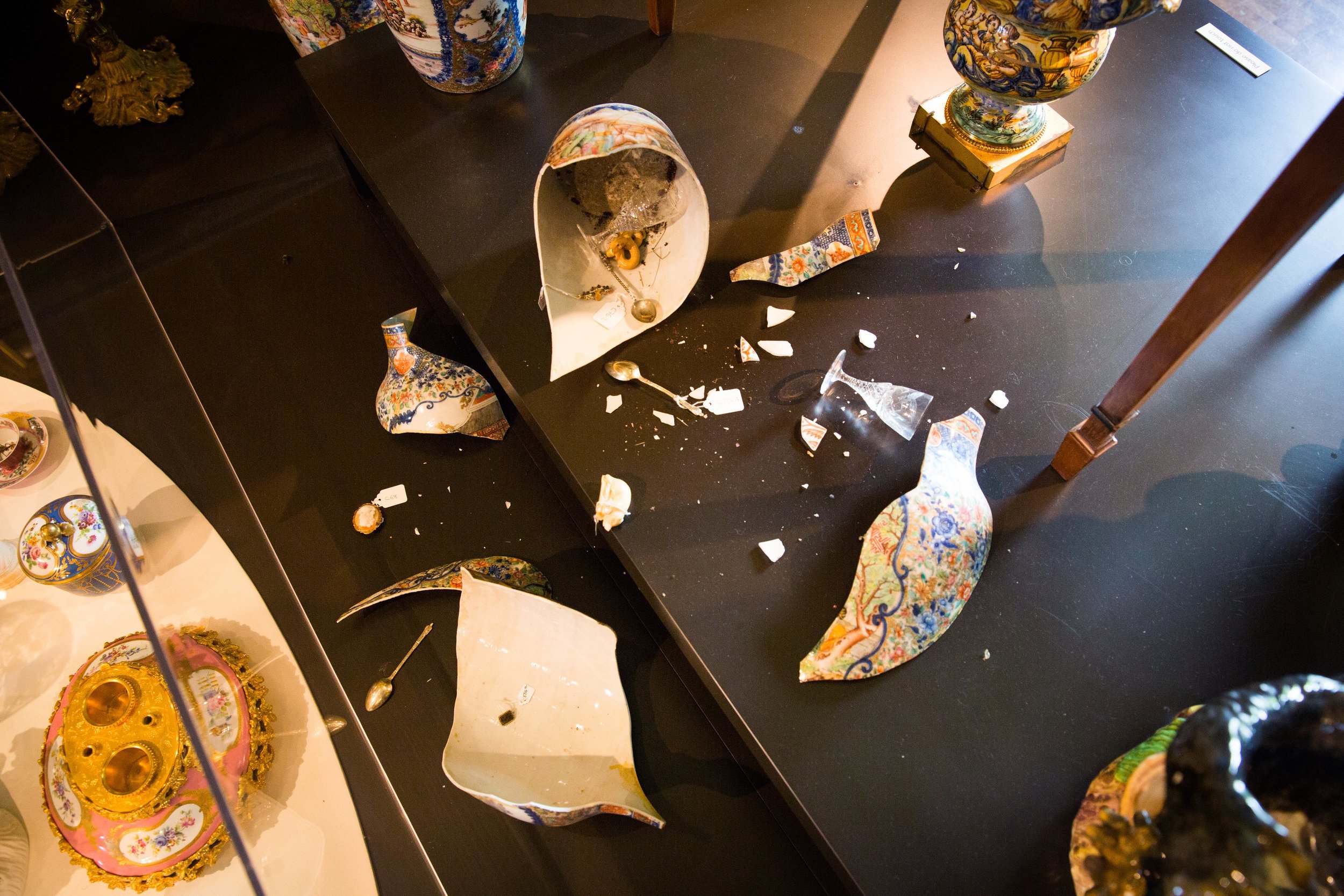 A toppled vase has smashed to reveal a hoard of stolen silver spoons, netsuke and jewellery. Flying skullships constructed from animal skulls, silver and broken ceramics are flown by enslaved insects. They deposit stolen objects into vases as they fly past. An angry swarm of honey bees, controlled by the fairies, spews from other vases.