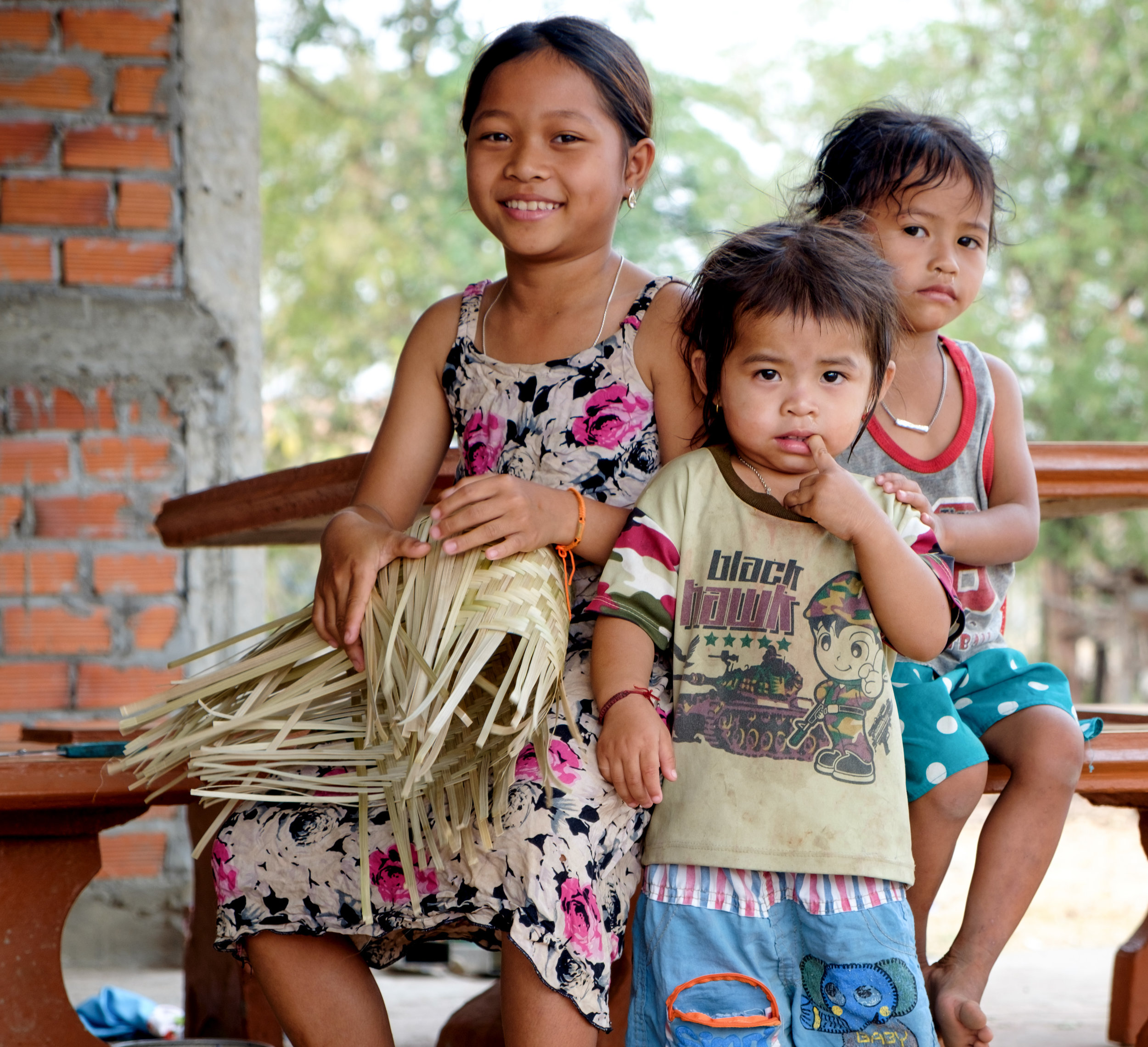 Jeune fille tressant un panier avec ses soeurs.