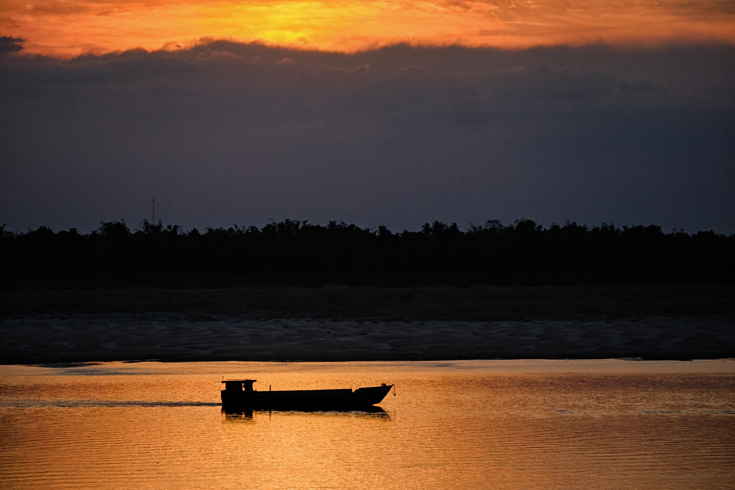 Pirogue au coucher du soleil sur le Mékong.