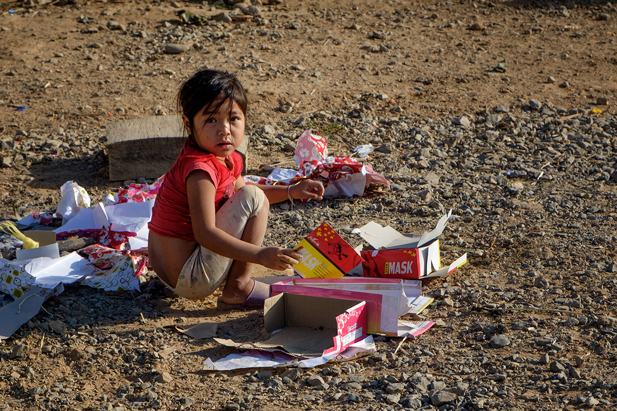 Une enfant joue avec des retailles dans un petit village du nord du Laos.