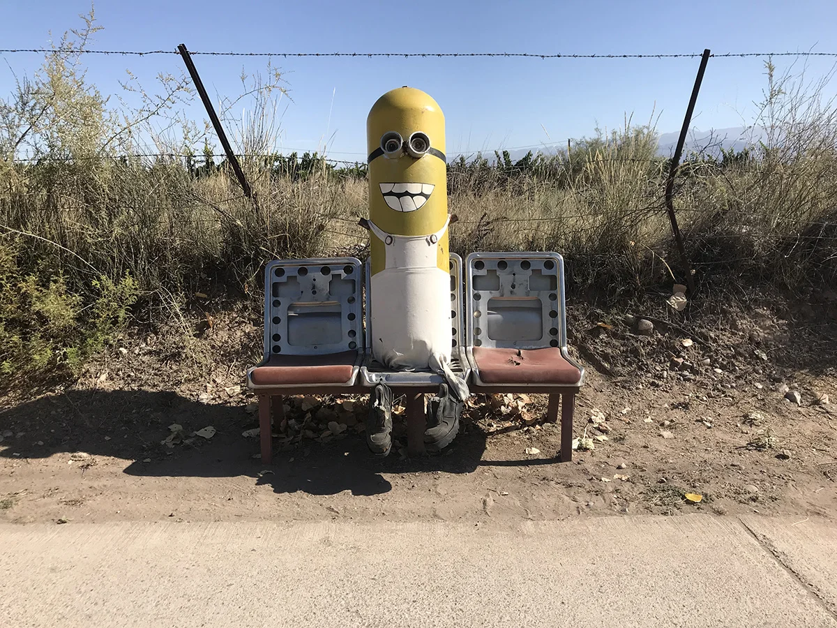 Une grosse bonbonne de gaz assise sur un banc, à côté d’un champ.