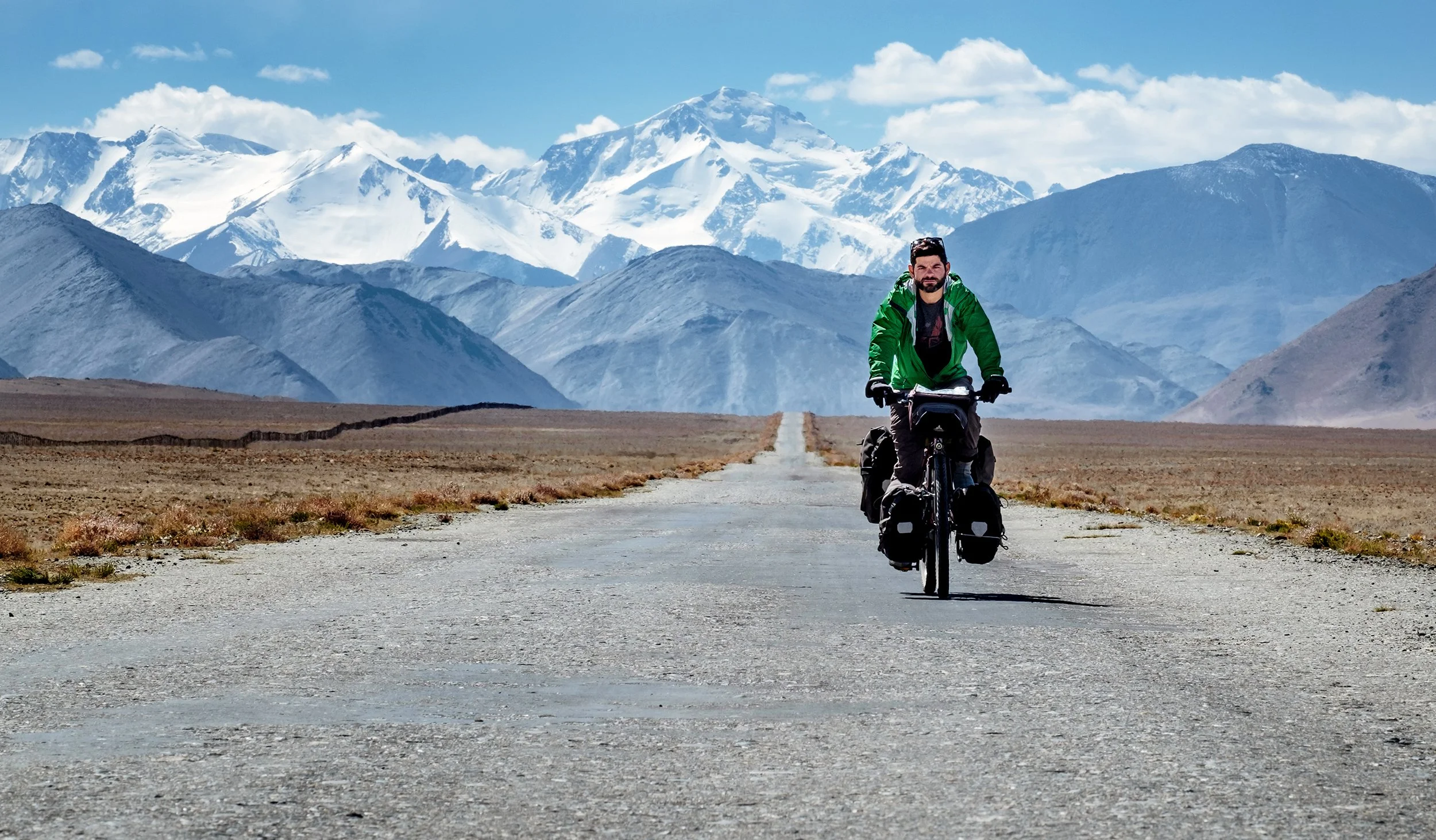 Jonathan à vélo sur une route du Pamir, au Tadjikistan