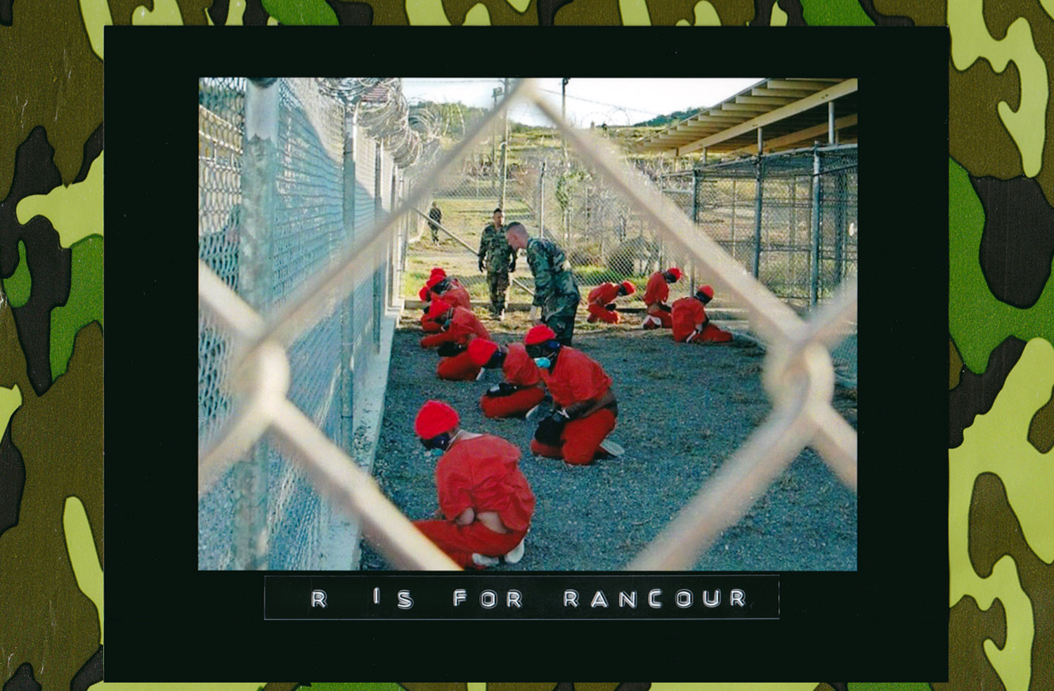 Detainees in orange jumpsuits sit in a holding area under guard by military police at Camp X-Ray inside U.S. Naval Base Guantánamo Bay, Cuba, during their processing into the temporary detention facility, Jan. 11, 2002. (Photo: U.S. Navy)