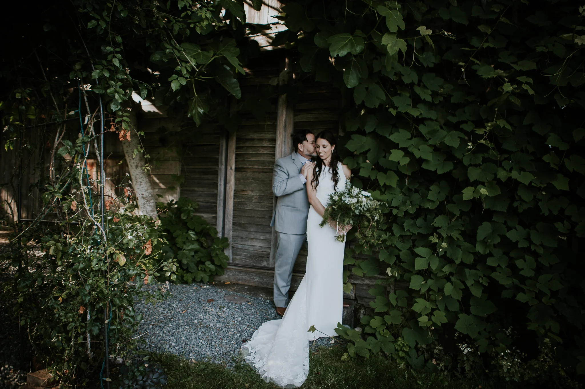 Bride and groom standing under climbing vines at vineyard wedding on Vancouver Island