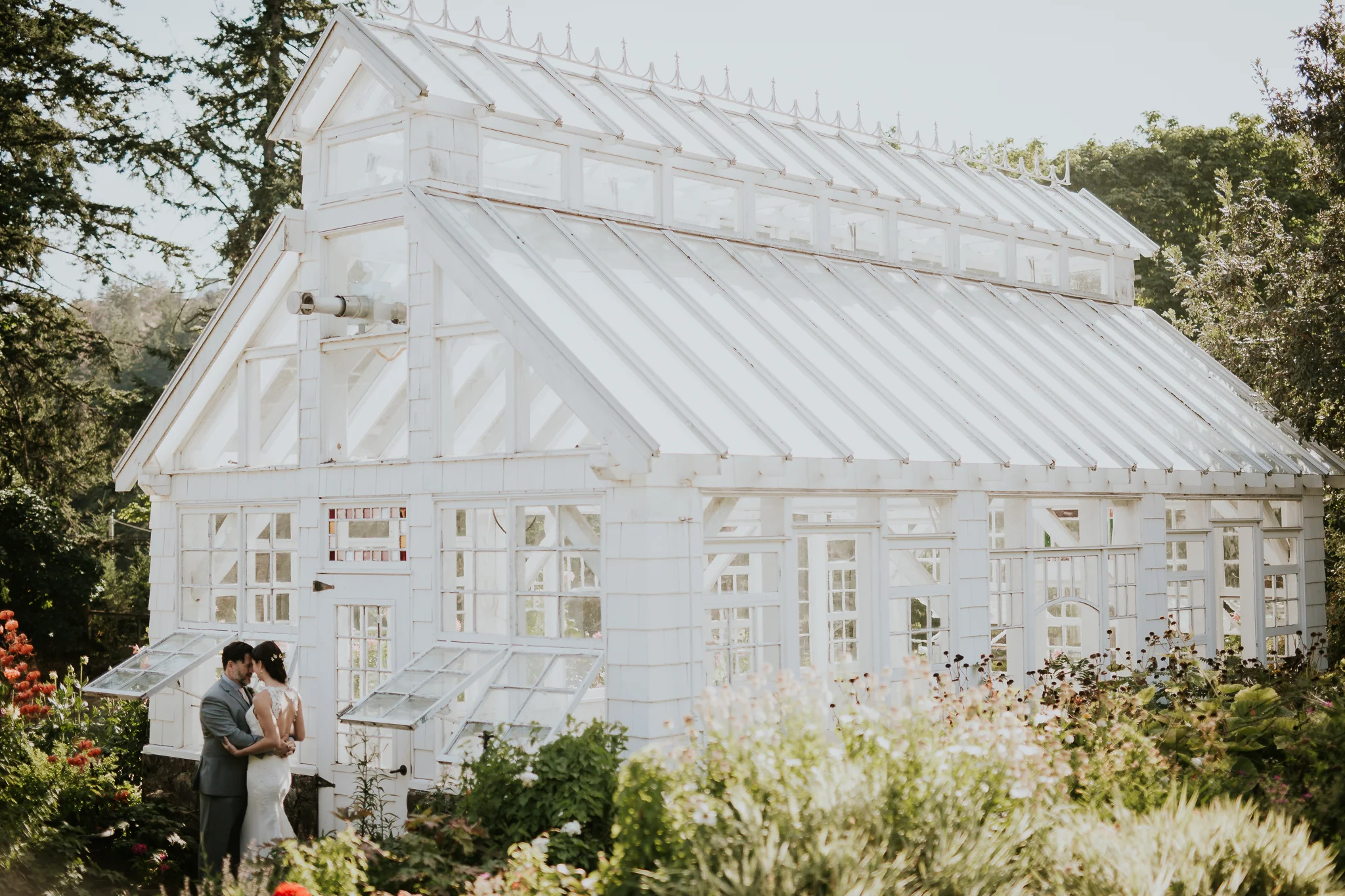 Bride and groom standing by greenhouse on Vancouver Island wedding venue