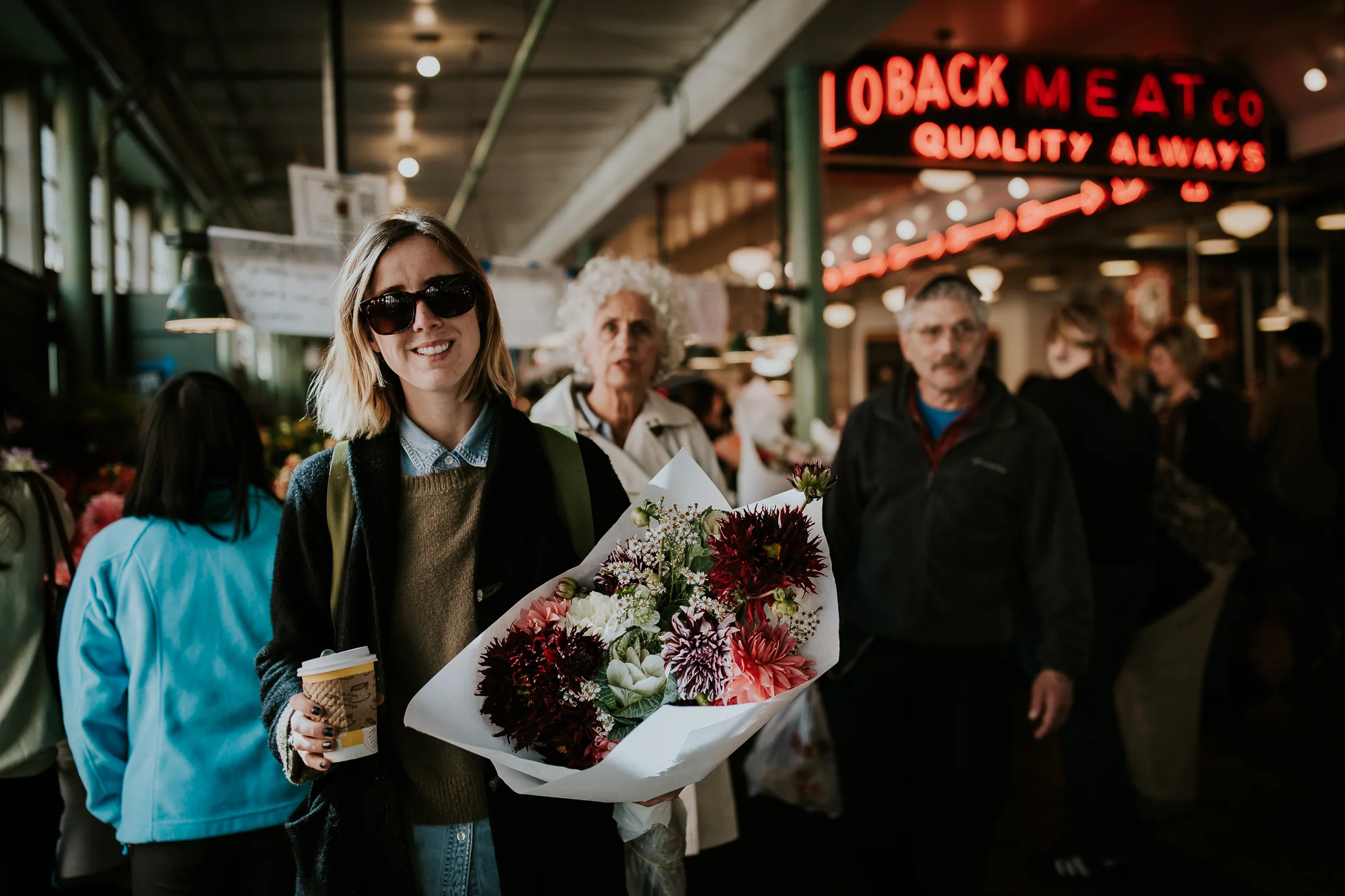 Tourist at Seattle Public Market holding coffee and bridal bouquet