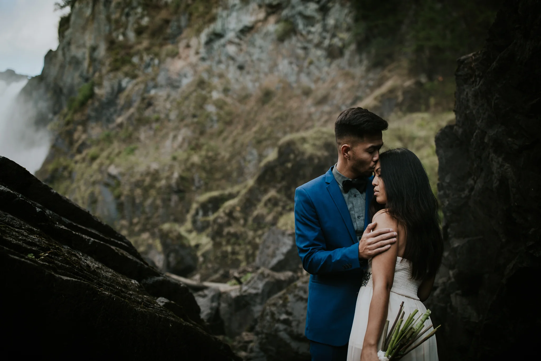 Groom kissing brides forehead during elopement at waterfall near Seattle Washington