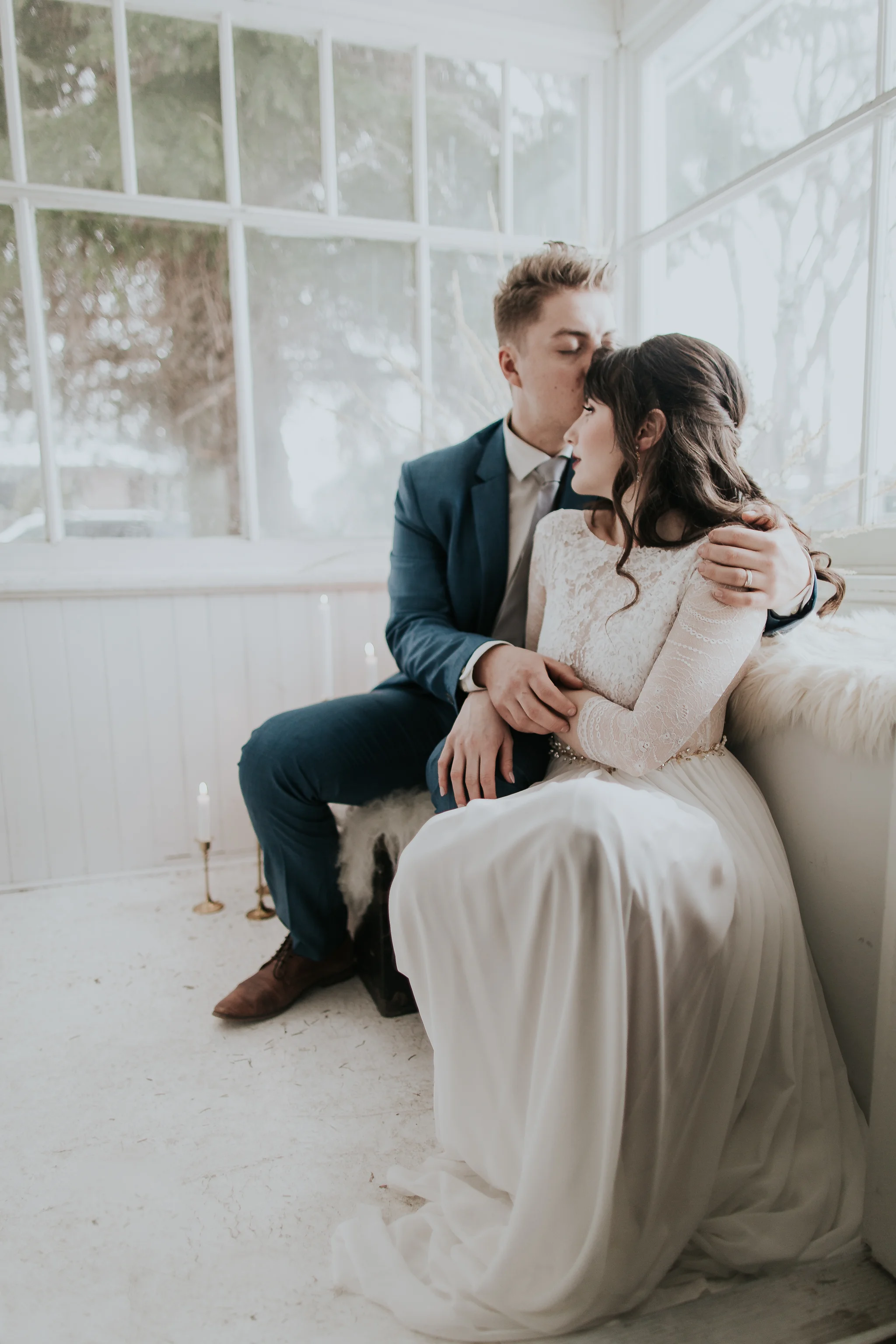 Bride and groom cuddling in sunroom during winter wedding in Waterton National Park