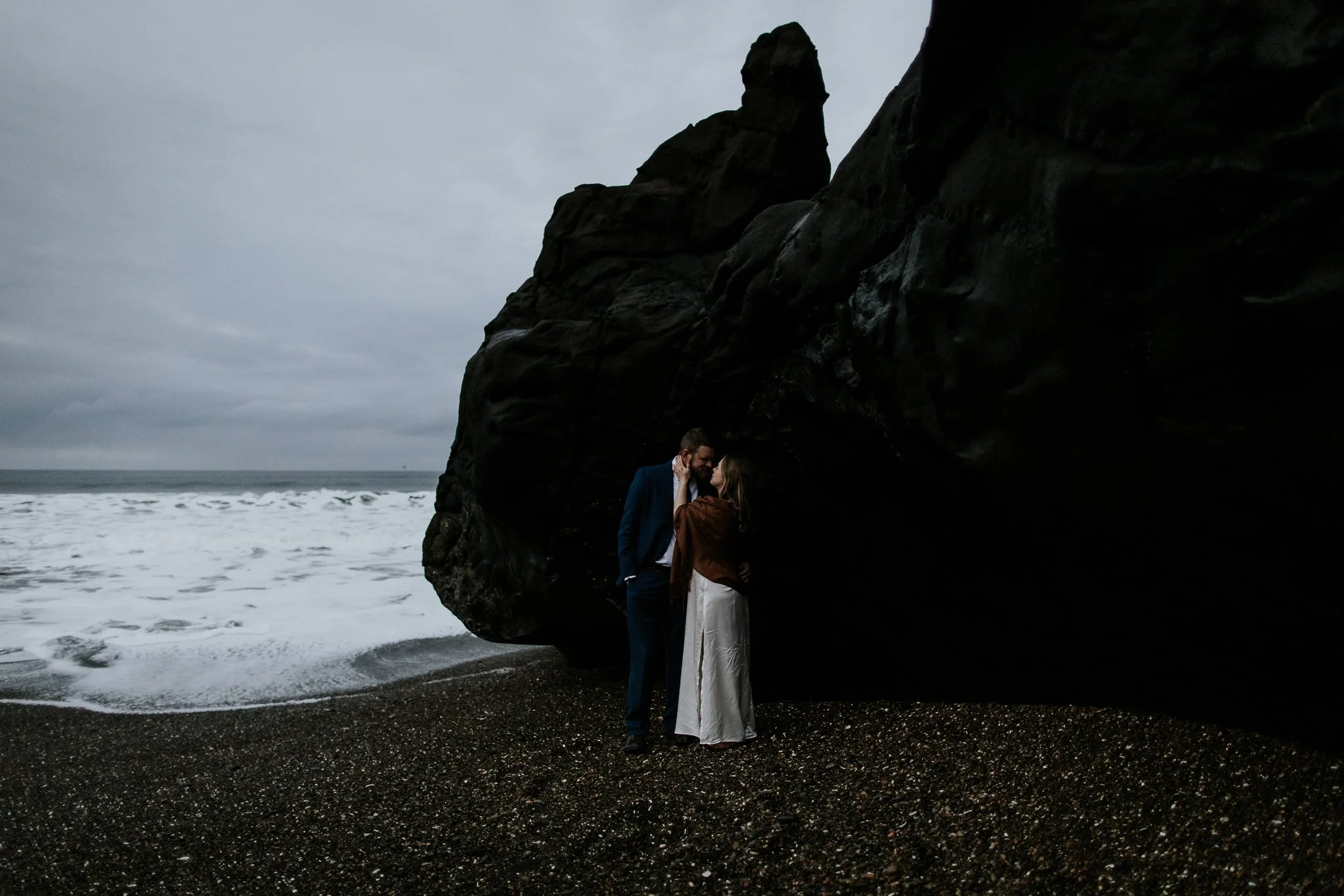  bride and groom standing on black sand beach looking into each others eyes during iceland destination wedding  
