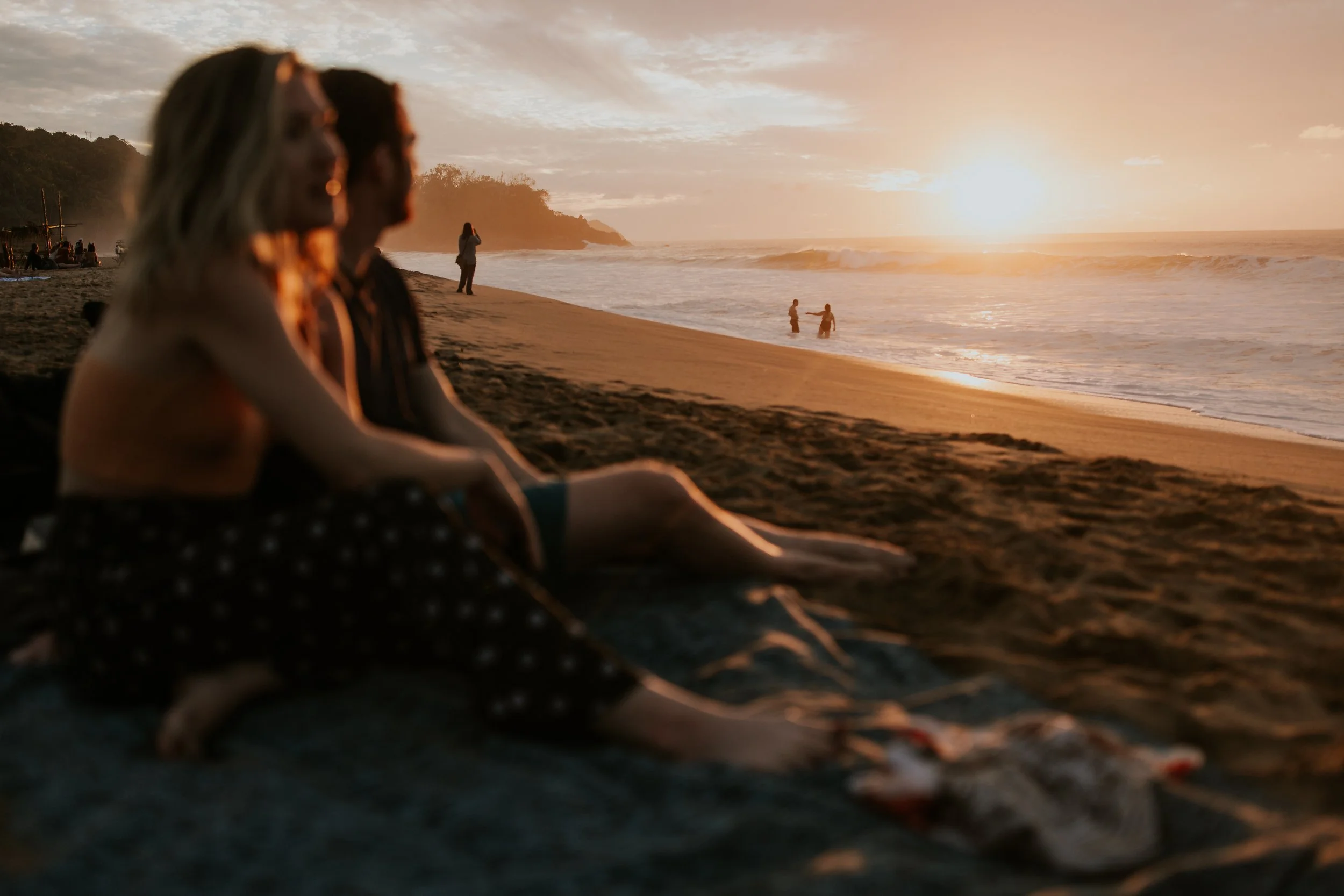 newly wed couple sits on the beach at sunset during destination wedding in mexico 