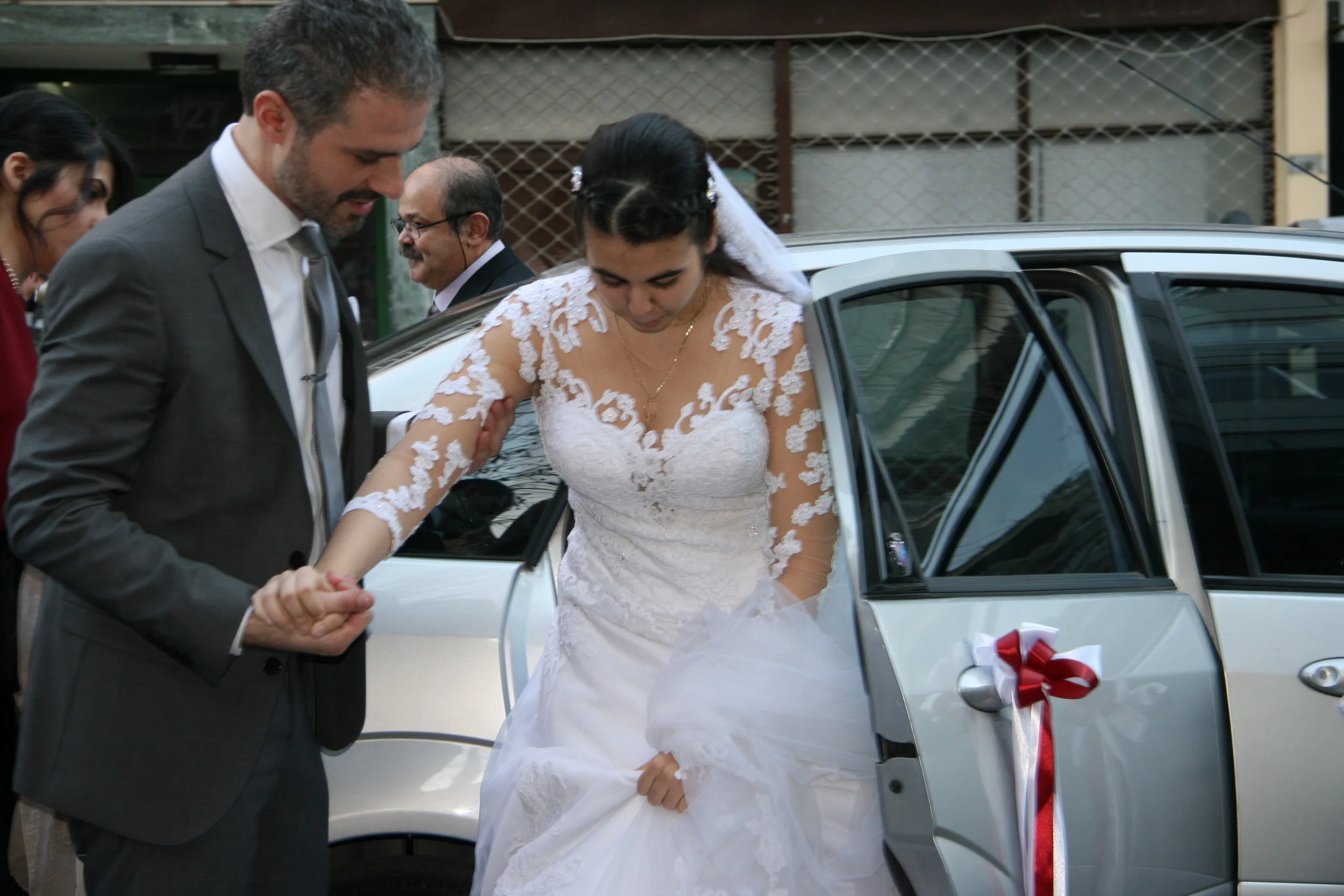 Best man helps bride out; sister and father in view