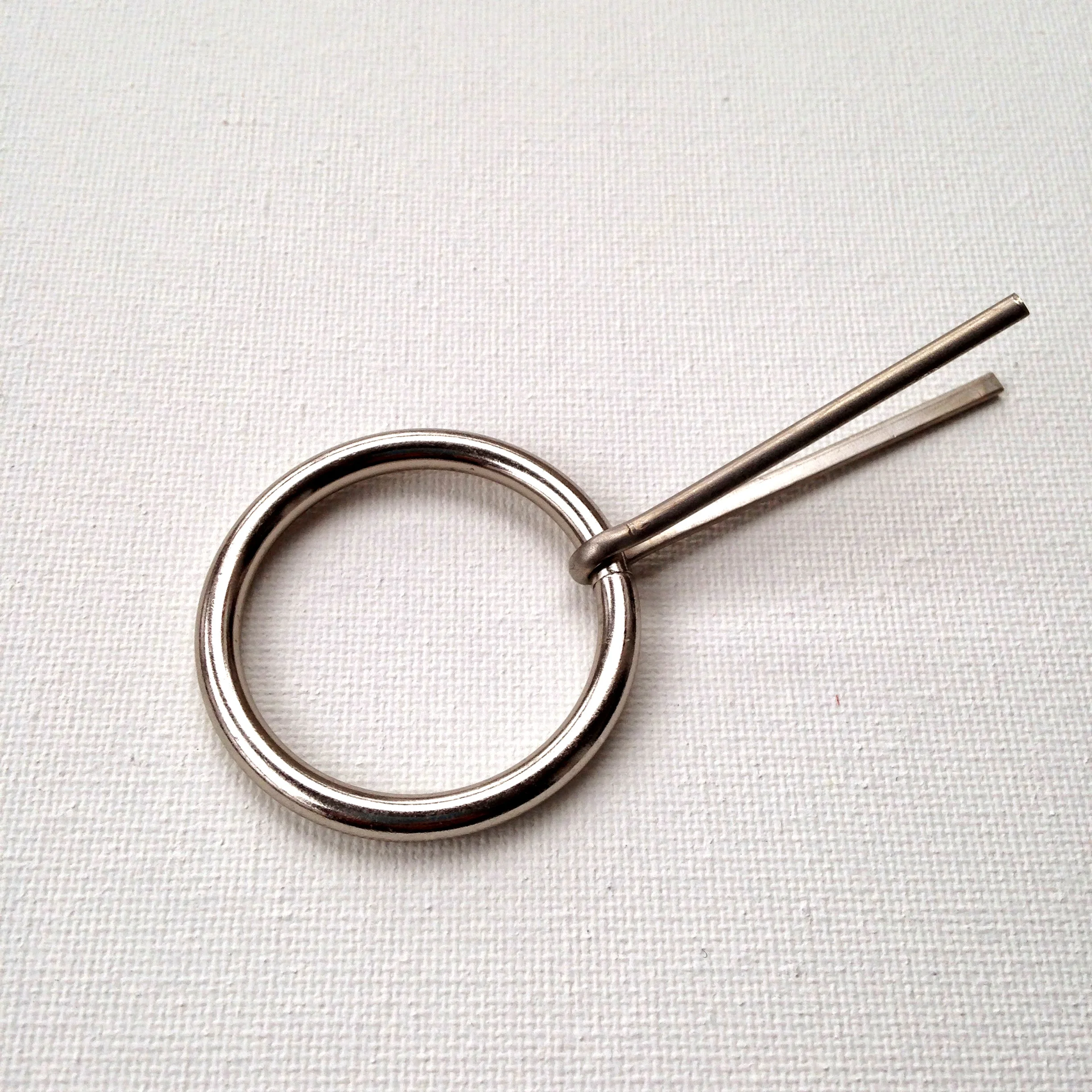 2. Much like sliding your finger through a bobby pin, slide the ring between the two prongs of the cotter pin until it reaches the eye at the end. Cotter pins are made from much tougher metal than bobby pins {which is good because you want something stronger for furniture pulls}. So this is really where you want to use pliers and put some elbow grease into it.