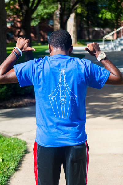 Cainan Ming shows off this years’ Project Impact t-shirt design. | PC: Zach Morrison
