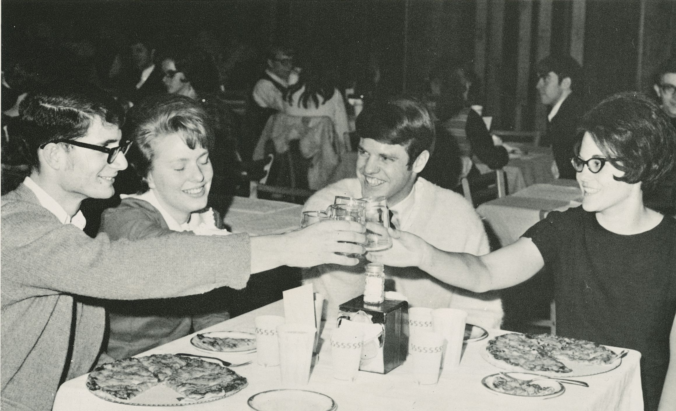PC: Yearbook: Group of students in cafeteria toast general activities night over pizza.
