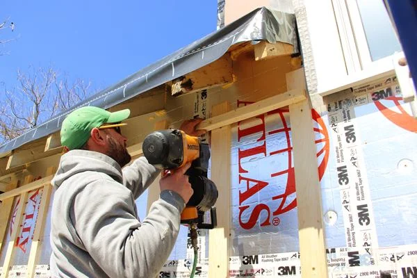 Carpenter Shane Fenton applies a a soffit nailer over the rain screen wall strapping.