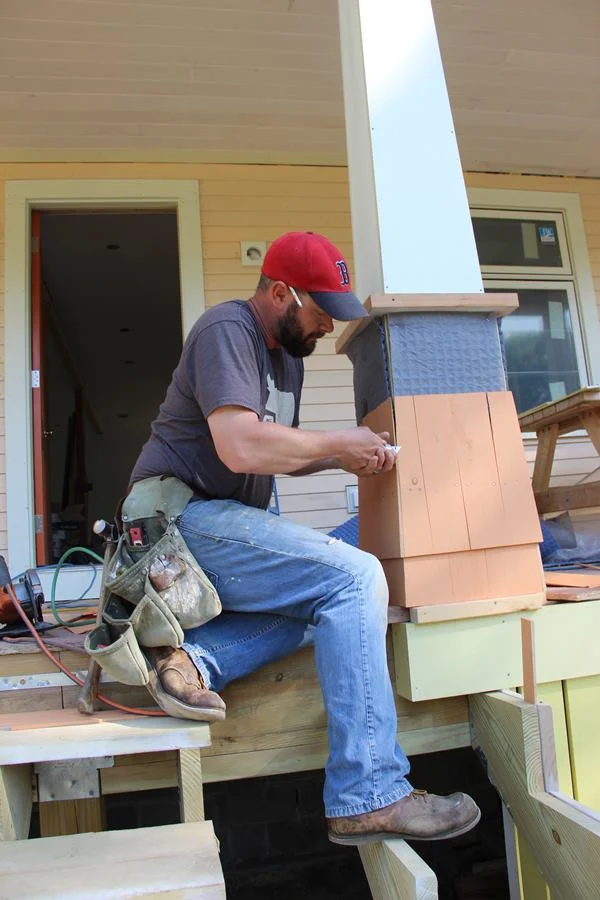 After nailing a corner shingle, Fenton fine-tunes the edge with a razor knife.