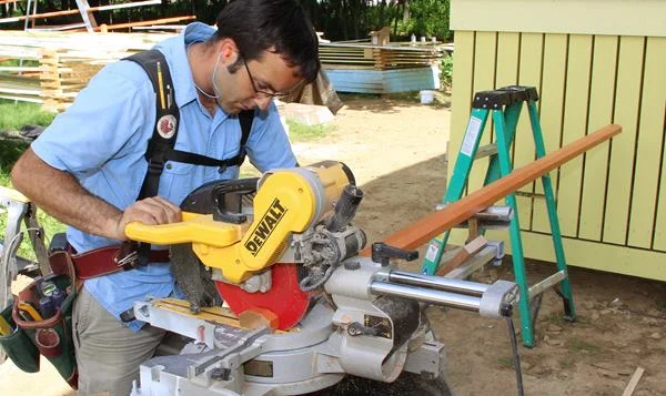 Cutting the pre-primed clear red cedar railing to fit on the radial-arm miter saw.