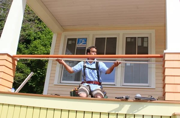 Pollard holds a top sub-rail in place before marking it and cutting it to length. This piece will be used to build the baluster assembly and fasten it in place.