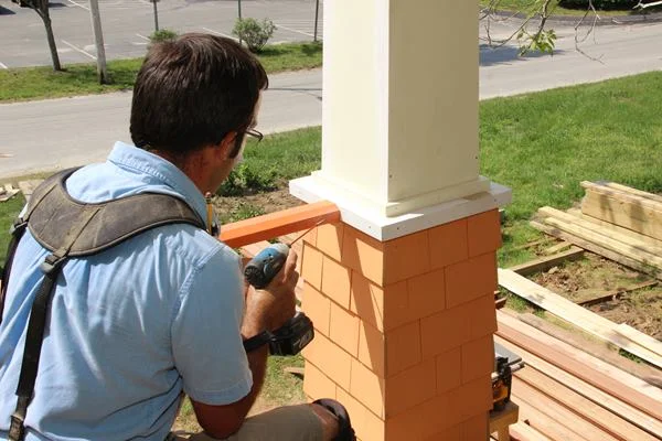 Attaching the railing to the porch column using #8 3-inch stainless steel screws.