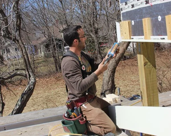Project lead Mark Pollard applies a polyurethane sealant to the primed miter of the beam trim.