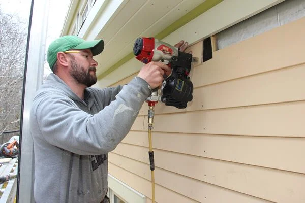 Fenton nails the end of a clapboard. Shown here is the scrap of asphalt paper, slipped behind the board to protect against rain intrusion if the joint opens up in service.