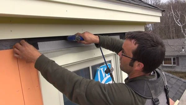 Tacking the window screen into place with a stapler.