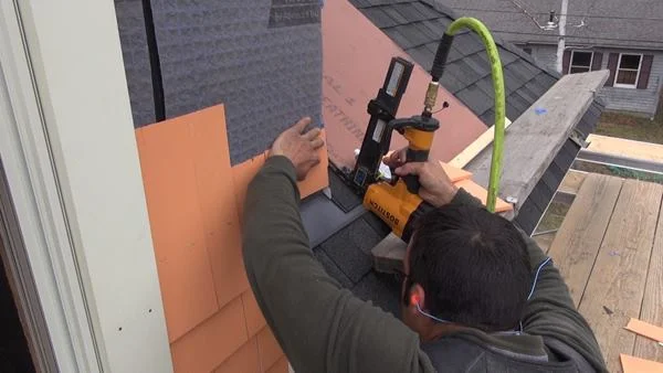 Pollard tacks up pieces of the thin ends of shingles for triple coverage above the roof.