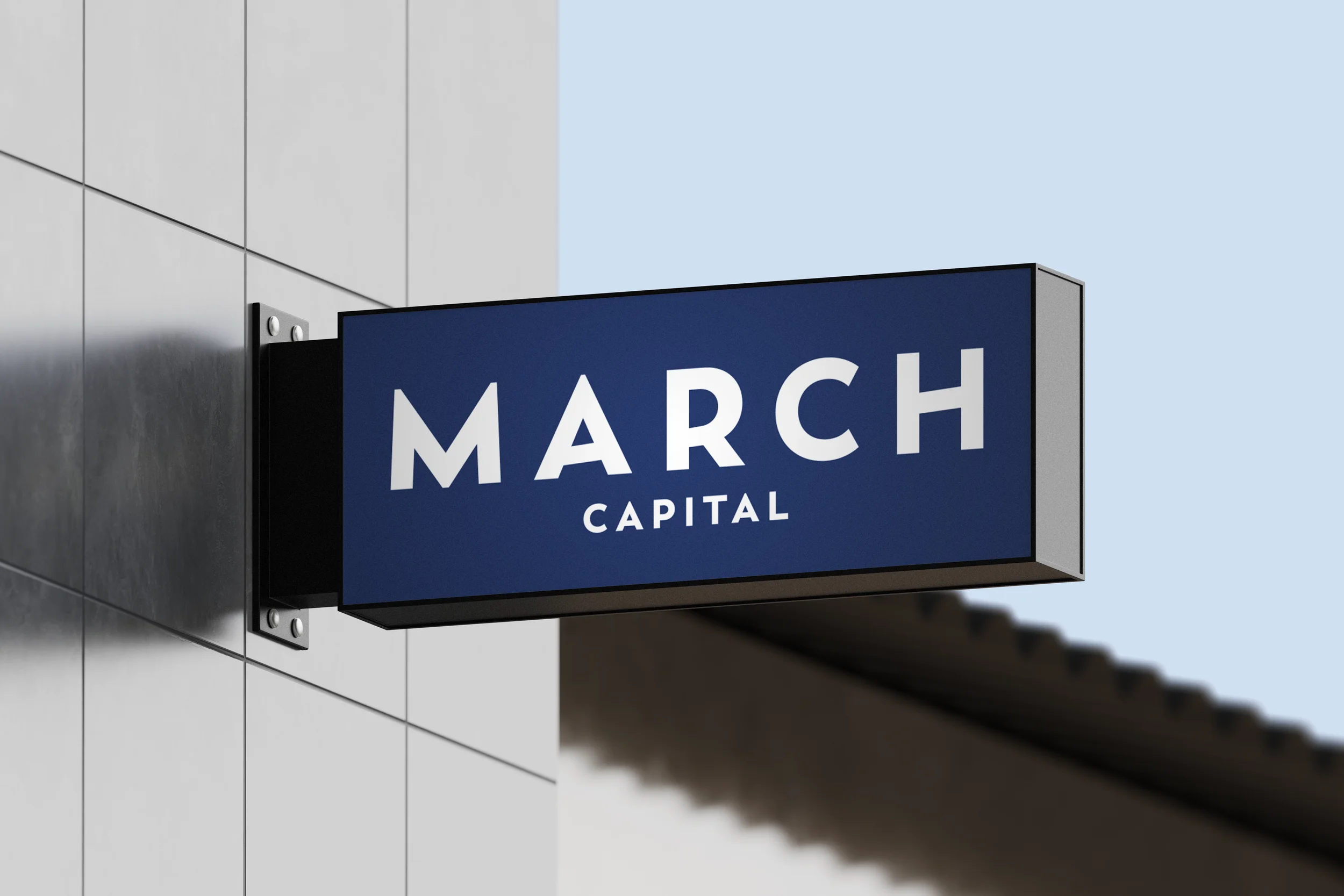 A blue rectangular sign with white text reading 'MARCH CAPITAL' mounted on the exterior wall of a building.